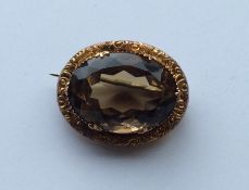 A 9 carat oval topaz brooch embossed with flowers