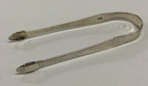 A pair of silver sugar tongs with bright cut decor