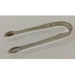 A pair of silver sugar tongs with bright cut decor