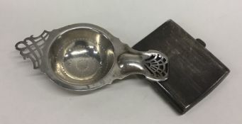 A stylish silver tea strainer together with an eng