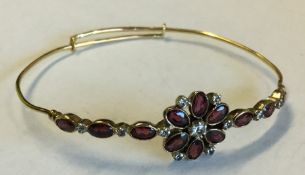 A gold and garnet mounted bangle with large centra