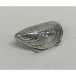 A silver pill box in the form of a mussel shell wi