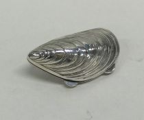 A silver pill box in the form of a mussel shell wi