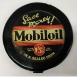 A circular "Mobiloil" oil drum lid mounted on wood