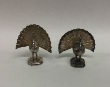 A pair of heavy cast silver peacocks on square bas