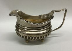 A silver half fluted cream jug decorated with flow