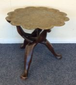 A small circular hardwood table with brass top. Es