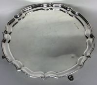 A circular silver salver with wavy edge on cabriol