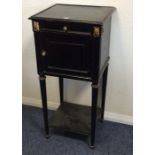 An ebony and gilt mounted bedside chest on taperin