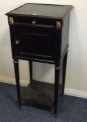 An ebony and gilt mounted bedside chest on taperin