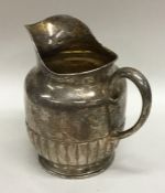 A silver half fluted cream jug on pedestal base. A