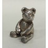 A small silver model of a teddy bear with textured