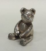 A small silver model of a teddy bear with textured