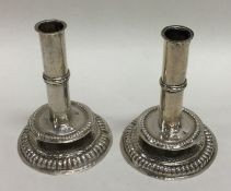 A pair of cast circular silver dwarf candlesticks