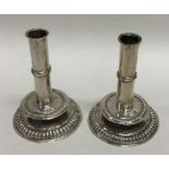 A pair of cast circular silver dwarf candlesticks