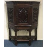 A large oak carved hall cupboard with shaped front