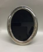 A large oval silver picture frame with rope twist