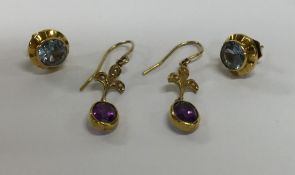 A pair of gold earrings together with another pair