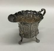 An Irish silver cream jug embossed with flowers an