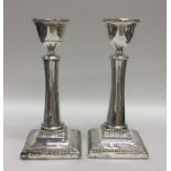 A pair of square based silver candlesticks with ba