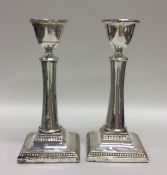 A pair of square based silver candlesticks with ba