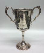 A silver two handled trophy cup embossed with flow