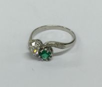 An emerald and diamond two stone crossover ring in