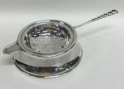 A heavy silver tea strainer on stand with pierced