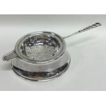 A heavy silver tea strainer on stand with pierced