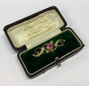 A pearl and pink stone brooch contained within a b