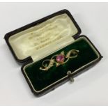 A pearl and pink stone brooch contained within a b