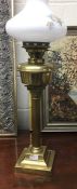 A brass Corinthian column lamp with glass shade.