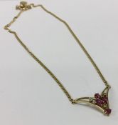 A 9 carat ruby and diamond drop pendant on fine li