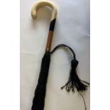 An ivory and ebony mounted umbrella with tassel dr