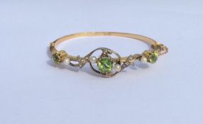 A large peridot and pearl hinged bangle with swirl