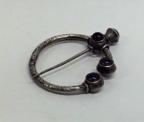 An unusual silver cloak pin engraved with scrolls