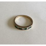 An emerald and gold half eternity ring. Approx. 2.