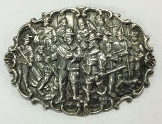 A cast silver brooch decorated with figures and sc