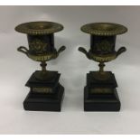 A pair of stylish brass urns mounted on slate base