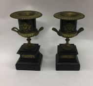 A pair of stylish brass urns mounted on slate base