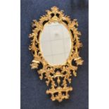 A large oval gilt mirror attractively decorated wi