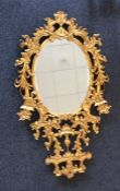 A large oval gilt mirror attractively decorated wi