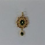 A peridot and ruby pendant in high carat gold. App