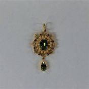 A peridot and ruby pendant in high carat gold. App