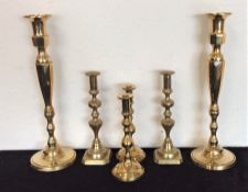 A pair of tall brass candlesticks together with tw