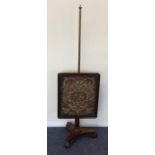 An Antique mahogany pole screen with scroll decora