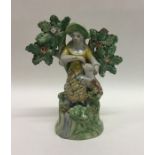 An early Staffordshire figure of a girl by a tree.