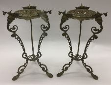 A pair of tall brass pedestals decorated with scro