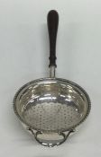 An Edwardian silver tea strainer with turned handl