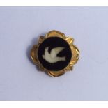 A small circular brooch decorated with a dove. App